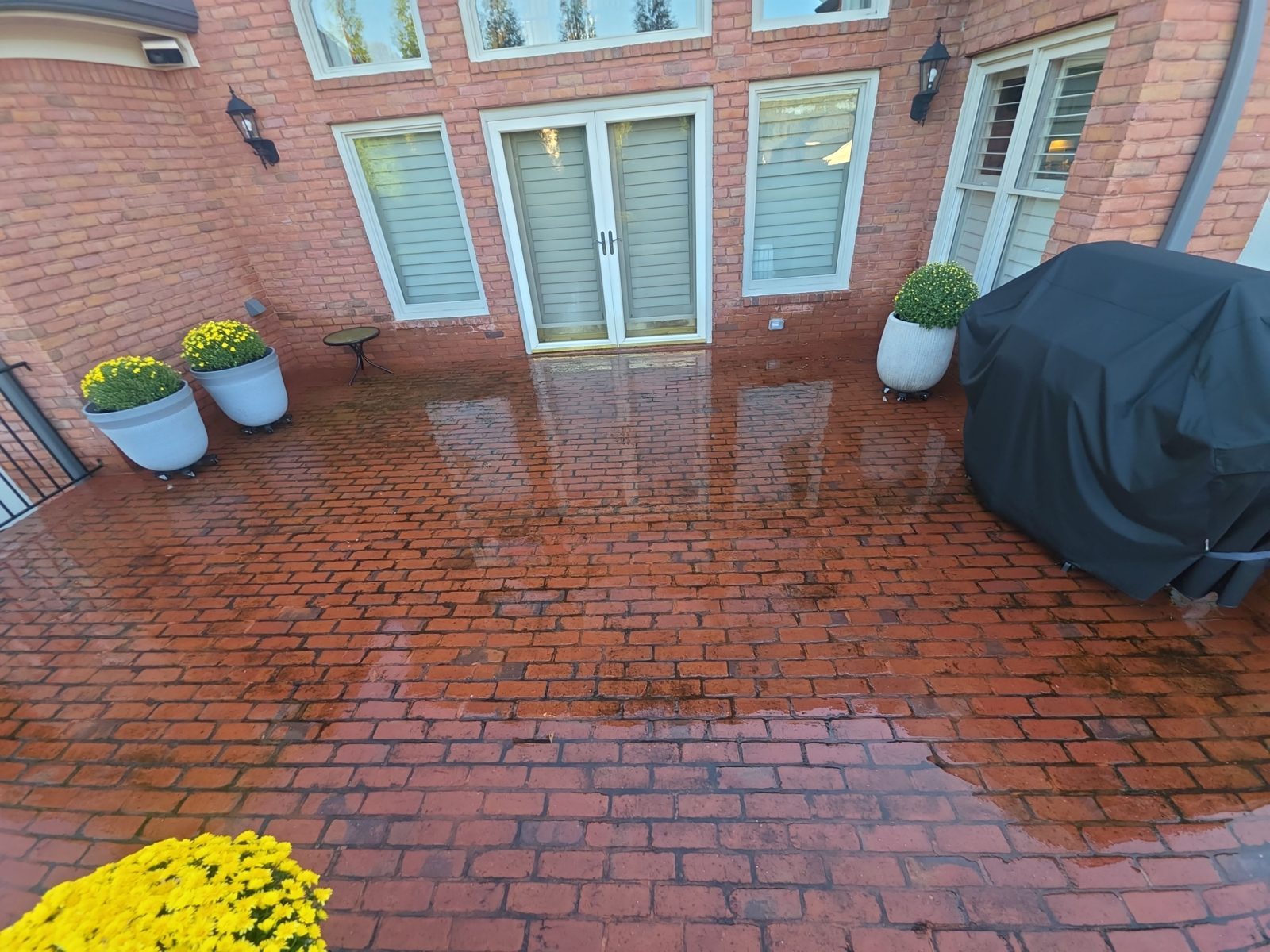 Brick side walkway in Thornberry after cleaning, red brick running beside the foundation, a downspout, and a small utility fixture