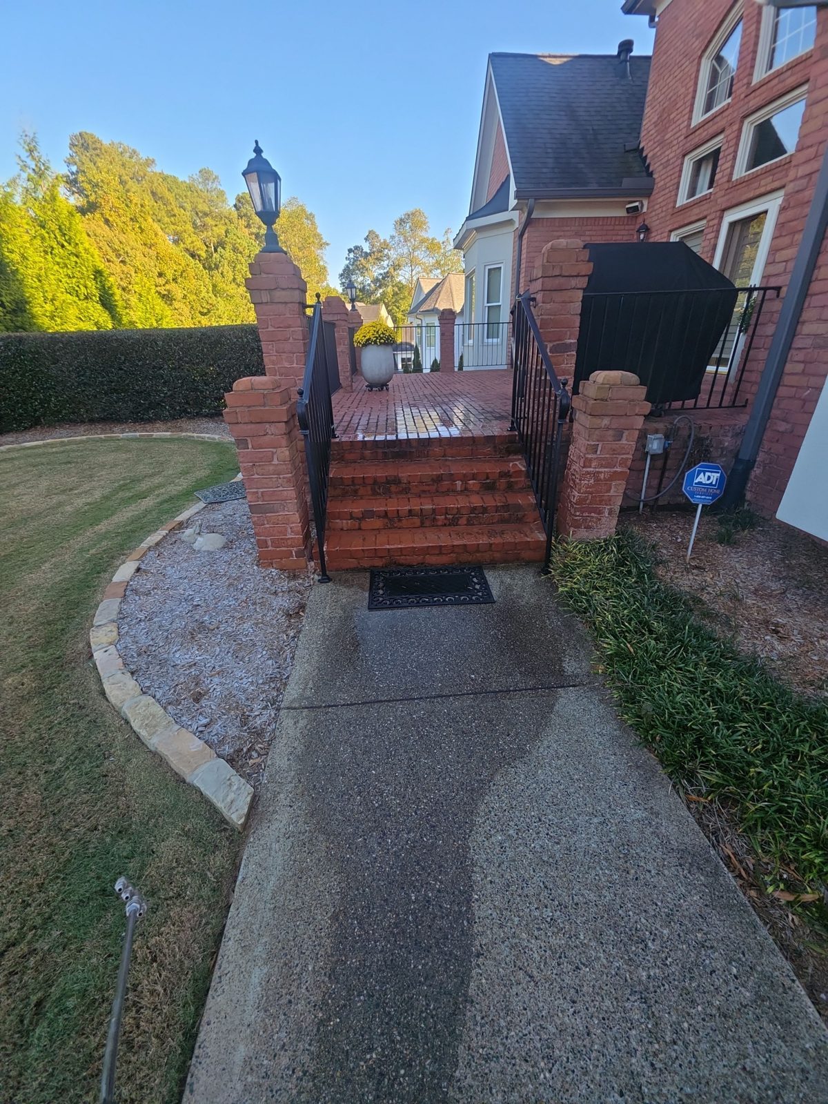 Brick steps beside a house in Thornberry before cleaning, with mildew on the treads and risers and a white downspout along the wall