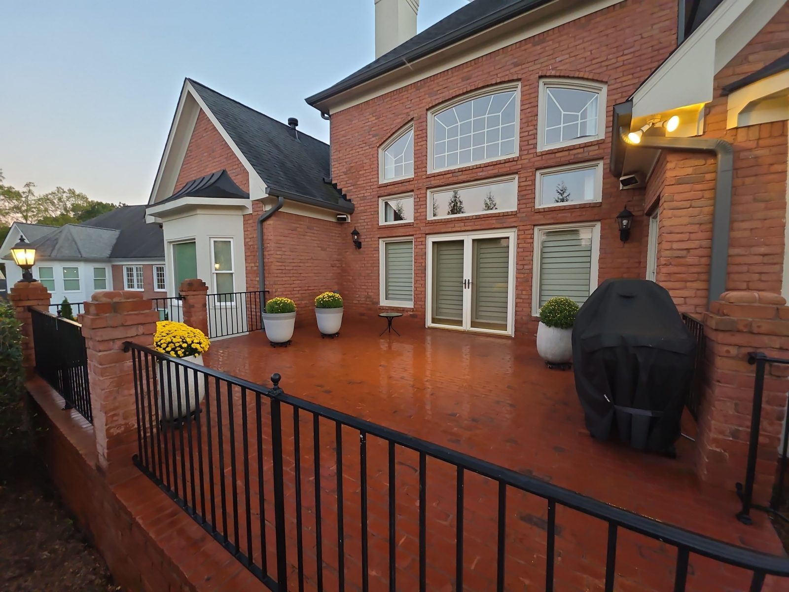 The raised brick terrace in Thornberry after cleaning, with red brick, black iron railings, and a light aggregate landing at the base of the steps