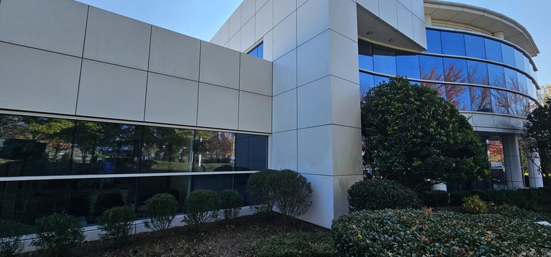 Exterior of a multi-story commercial building with glass and panel facade