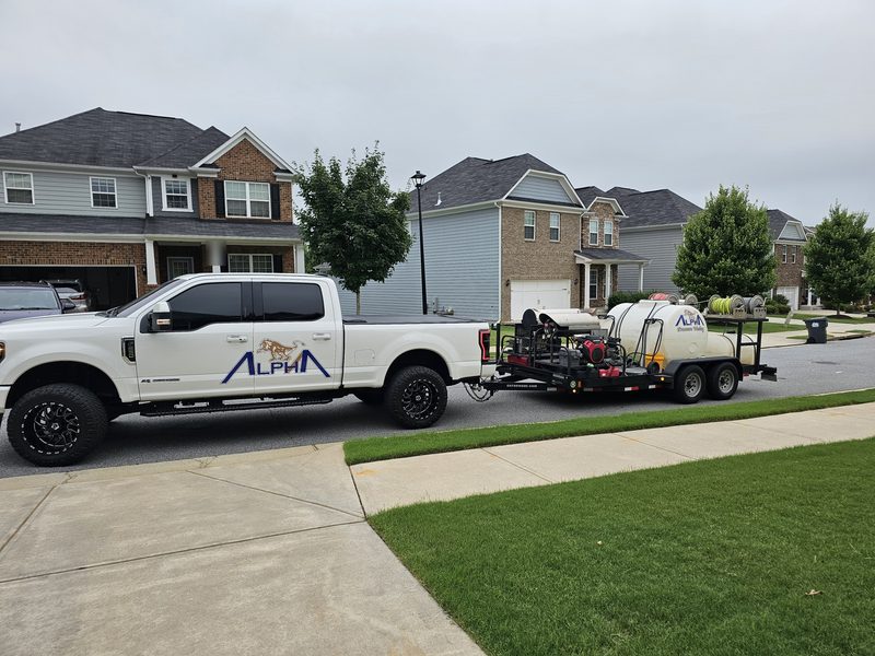 Alpha Pressure Washing pickup truck towing a trailer with a pressure washing rig, water tank and hose reels